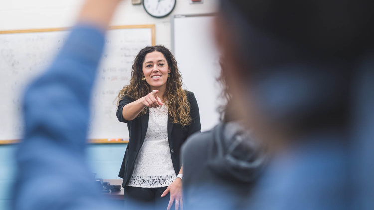 Female teacher calling on student with hand raised