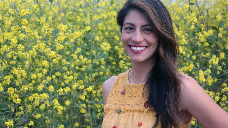 Photo of Yenda Prado in front of yellow flowers