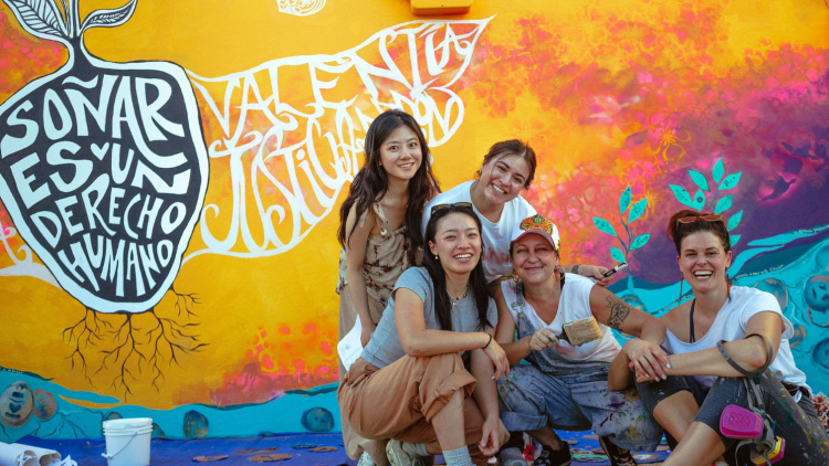 HGSE students in front of a bright-colored mural 