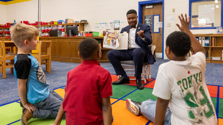 James Austin reads a picture book to three students