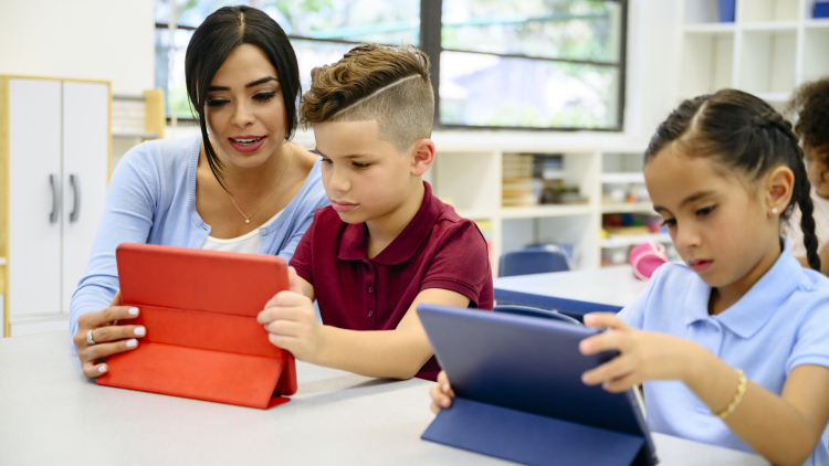 Teacher helps students working on a laptop