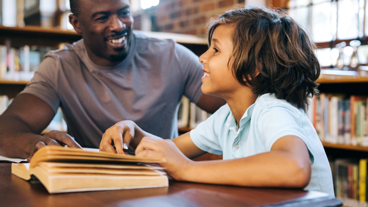 Male tutor with elementary student in library