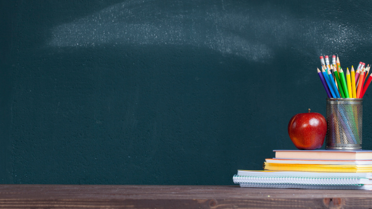 Pencil tray and an apple on notebooks on school teacher's desk
