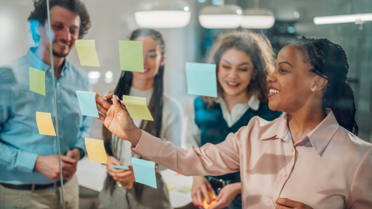 A team collaborating on a project, using sticky notes on a glass wall