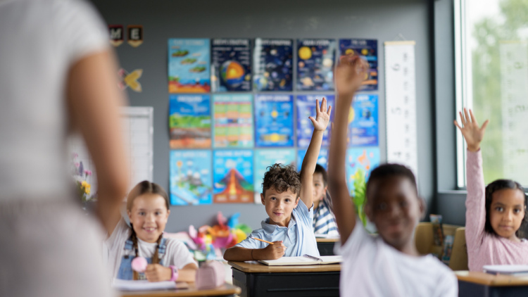 students raise their hands in middle school science class