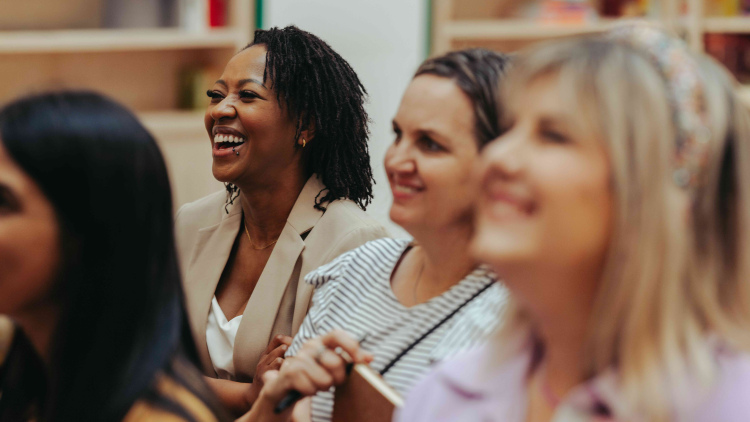 Diverse group of people smiling and engaged in a business meeting, conveying a sense of collaboration and positivity. The atmosphere is professional yet friendly, highlighting teamwork.