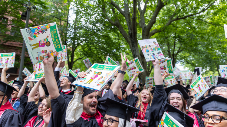 Students at the Harvard Commencement with their copy of Mychal Threets' book titled "I'm So Happy You're Here"