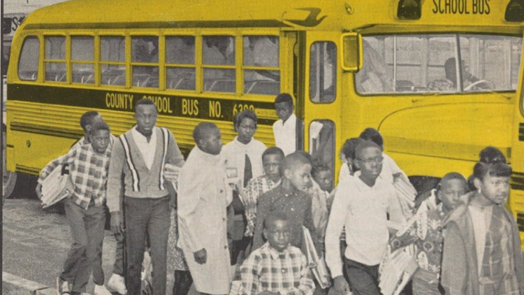 A black and white photo of Black students getting off a school bus in the 1970s