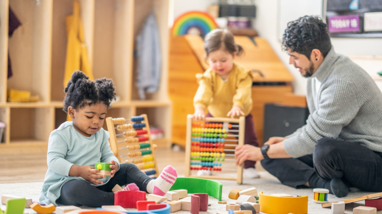 Preschoolers and their teacher play with blocks 