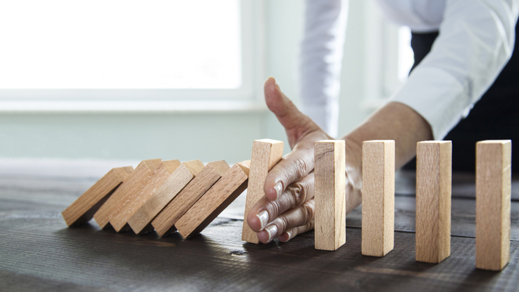Hand stopping dominoes from falling