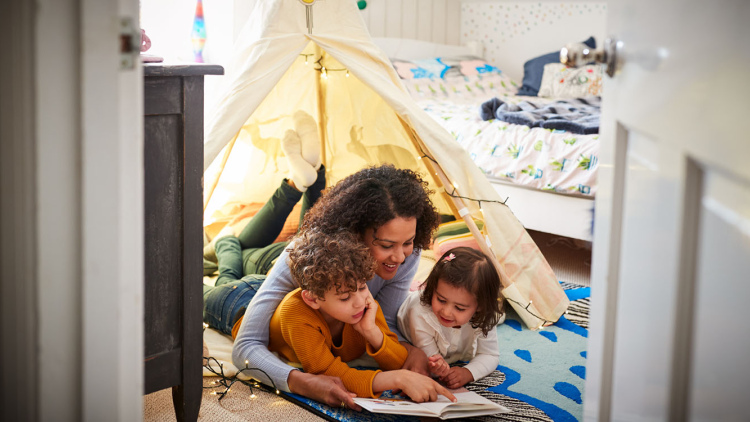 Mother reading to son and daughter in play tent