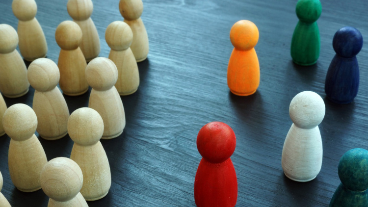 Natural-wood figures on left, with several colored-wood figures on the right, suggesting exclusion