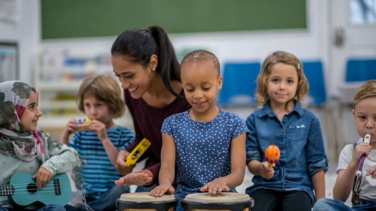 a diverse group of young students playing musical instruments with a teacher