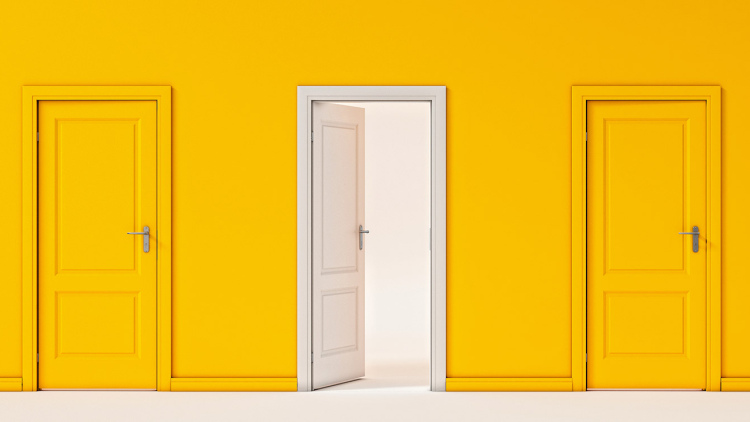 two closed yellow doors against a yellow background, with one white door that's open to light