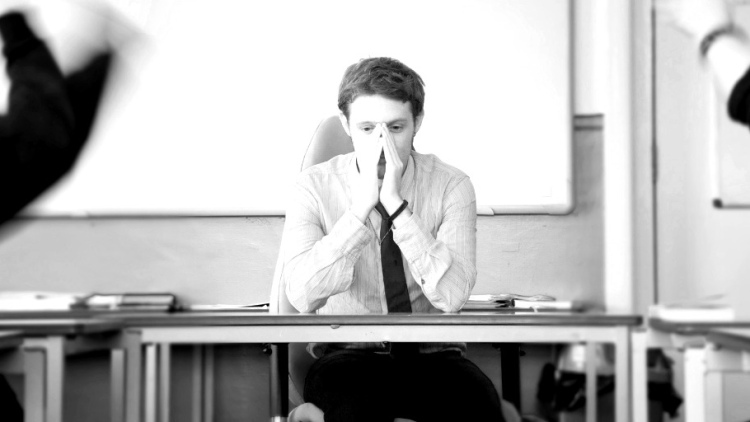 Teacher at desk with head in hands