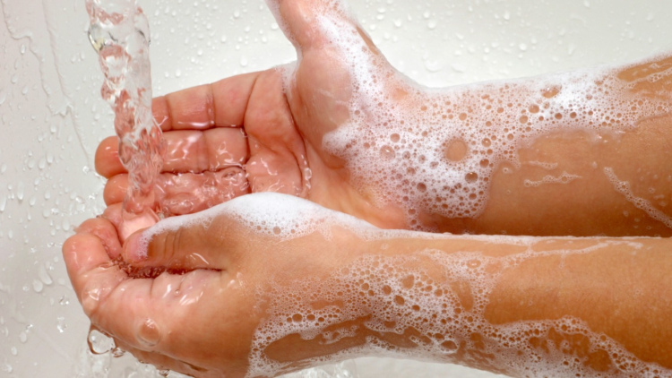 a child's soapy hands under running water