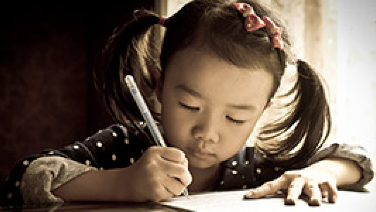 A young girl writes on a piece of paper