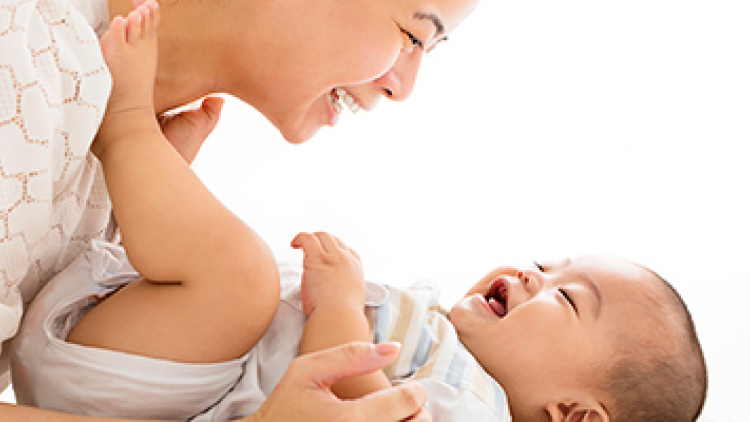 A laughing mother looking down at her smiling baby