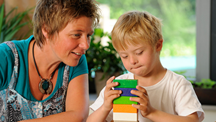 Teacher with a young child building a block tower