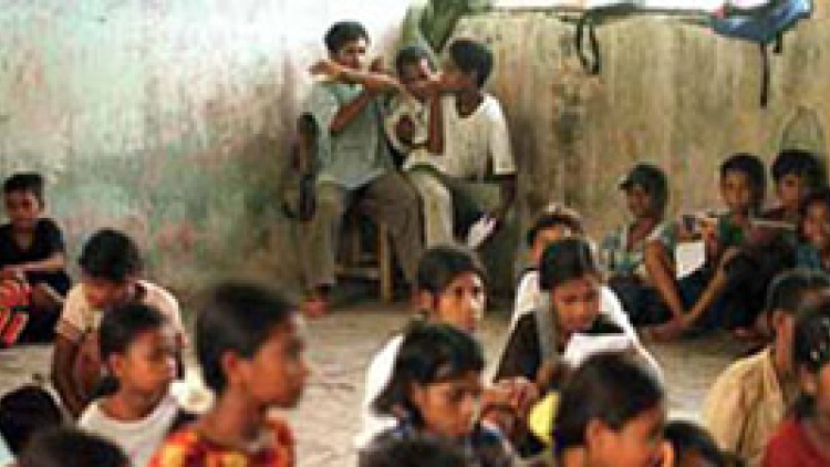 Three students at a school in Suai in Timor-Leste struggle to share the only chair in their classroom. (AP Photo/Simon Thong)