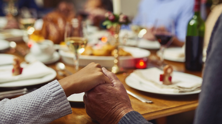 Photo of two people holding hands in front of a Thanksgiving table