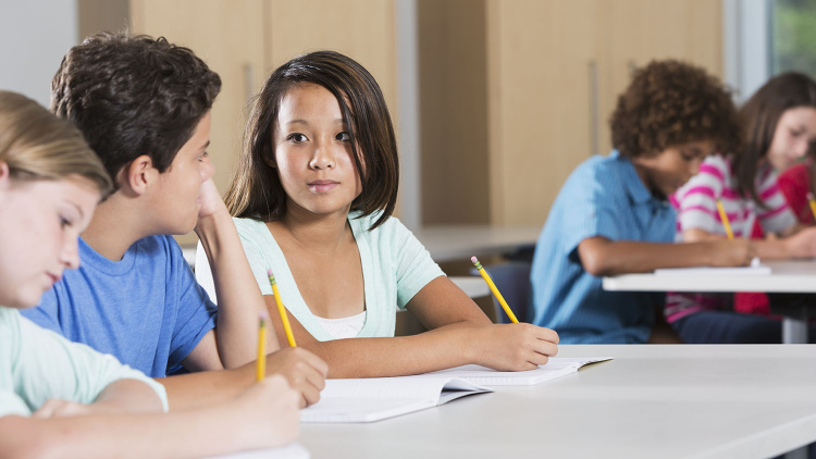 Photo of a female middle schooler looking seriously at a male classmate