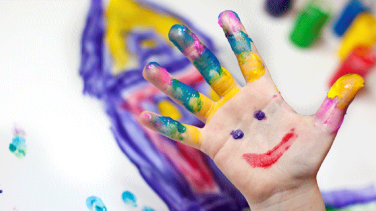 A child's hand covered in finger paint