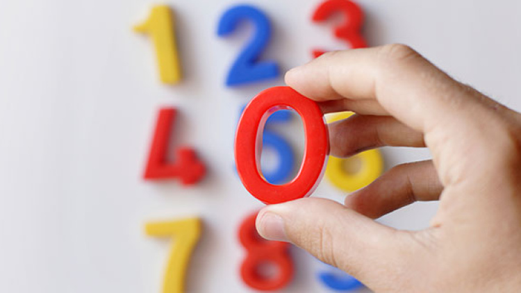 a child's number magnets, with hand holding a zero