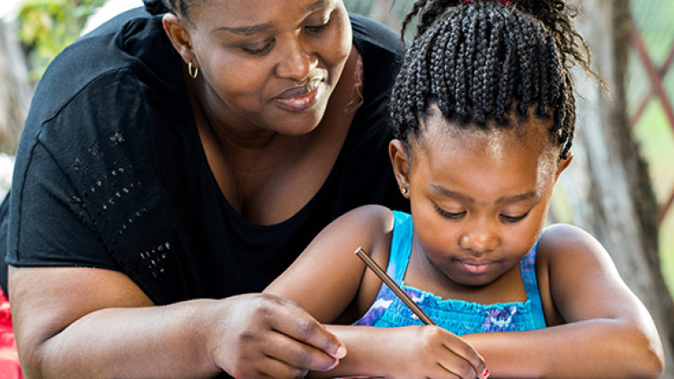 African American mother and her young daughter doing homework