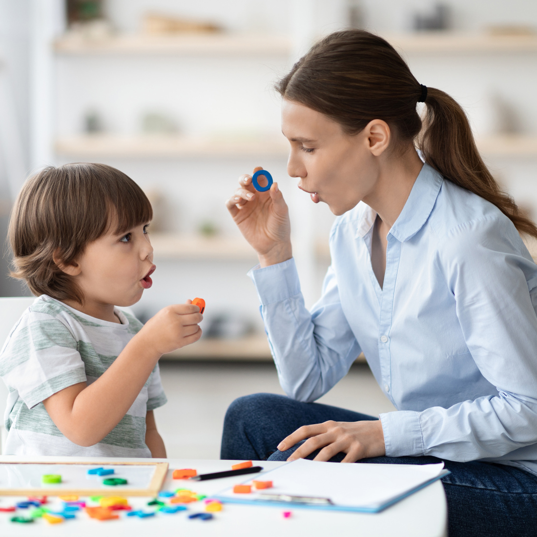 Little boy learning letter O with a teacher.
