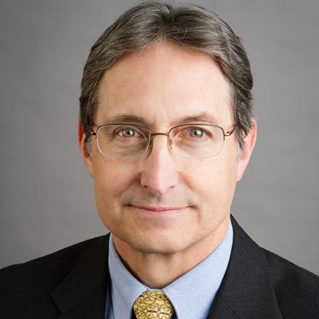 Headshot of Dutch Leonard, wearing a suit and glasses