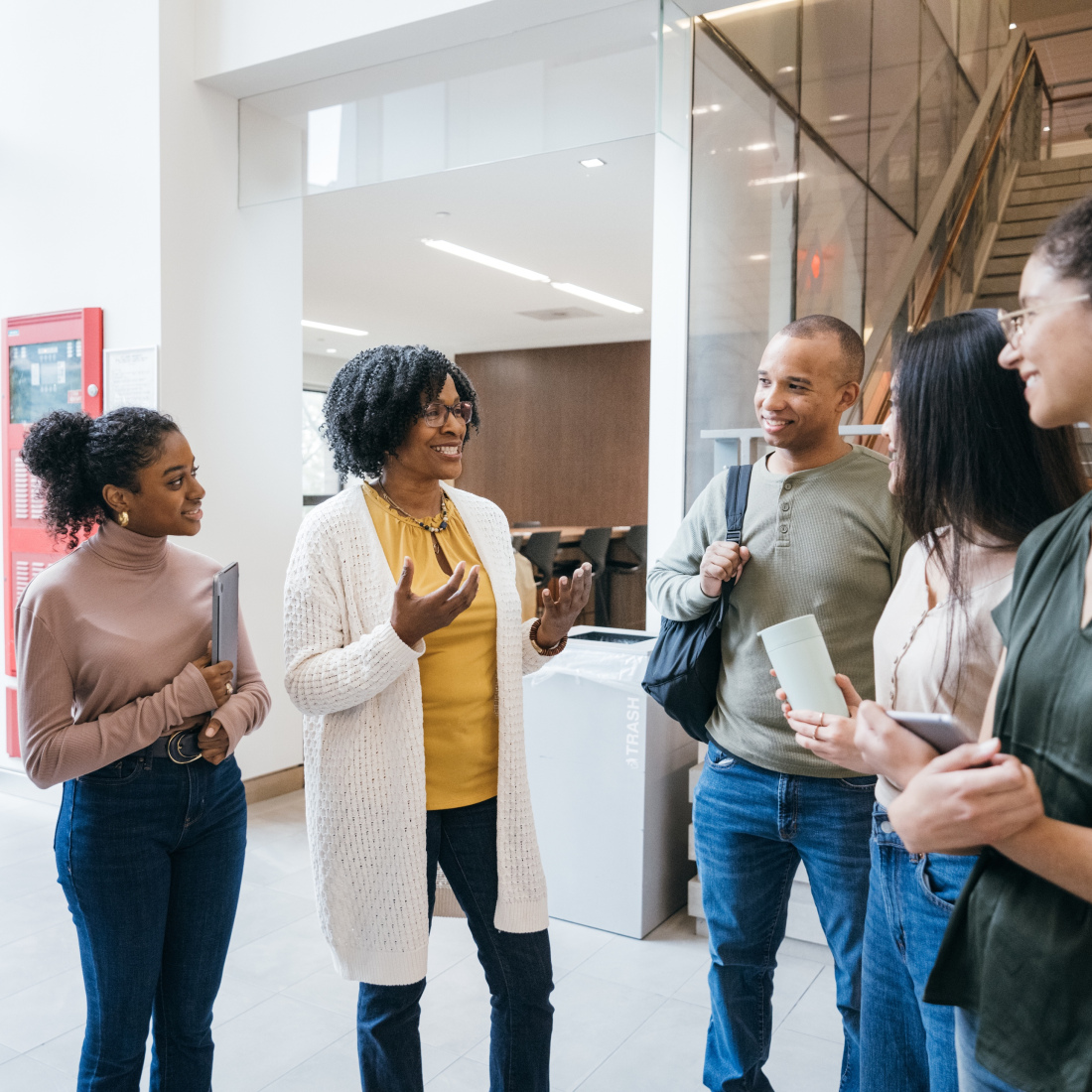 Teacher talks to diverse group of students in school lobby