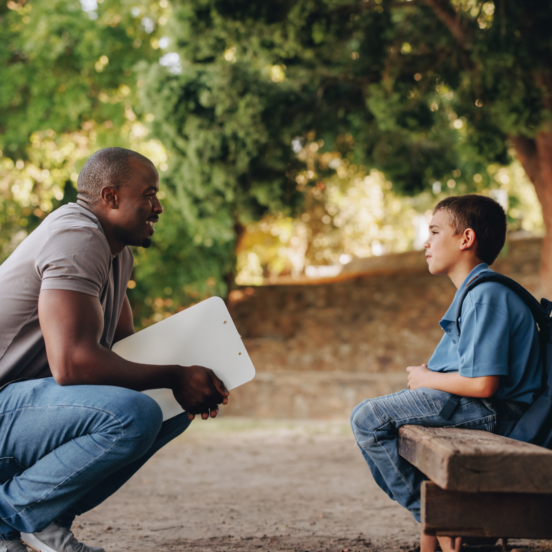 Counselor talking to a young school kid outside class, providing support and encouragement.