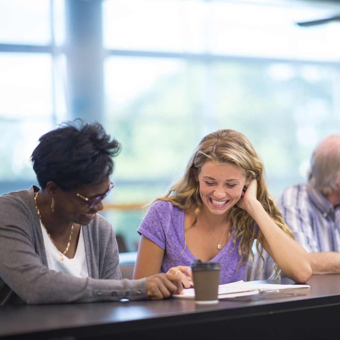 Higher education leaders help students at a table.