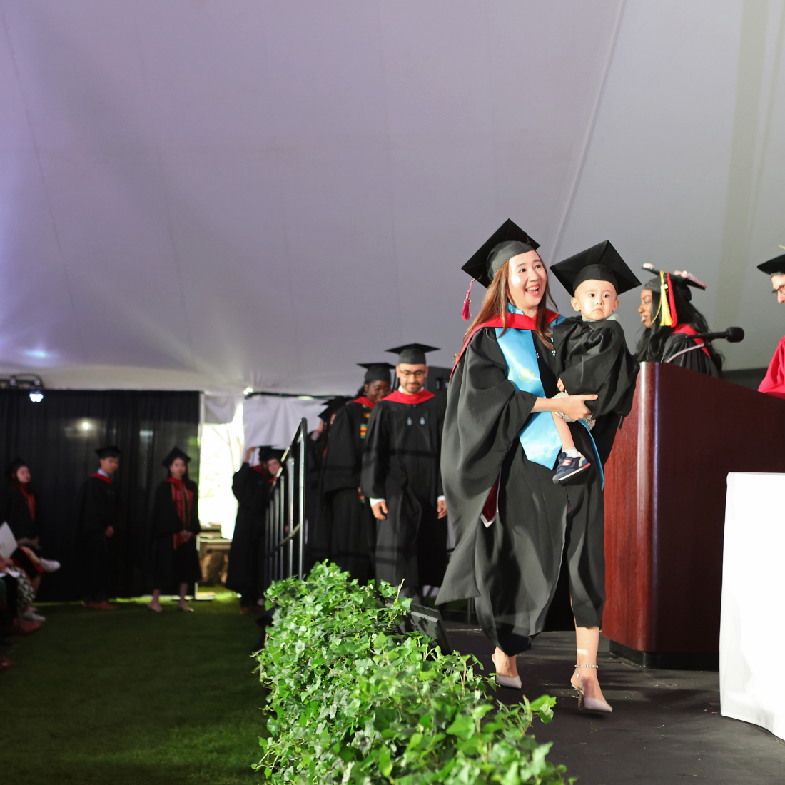Graduate with child crossing stage