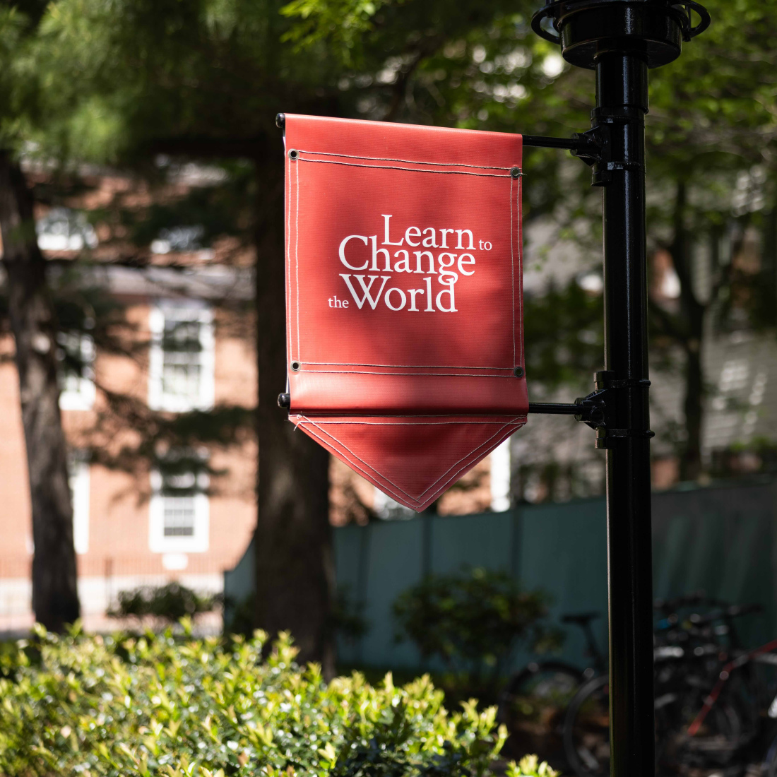Crimson flag that reads "learn to change the world" on campus at HGSE