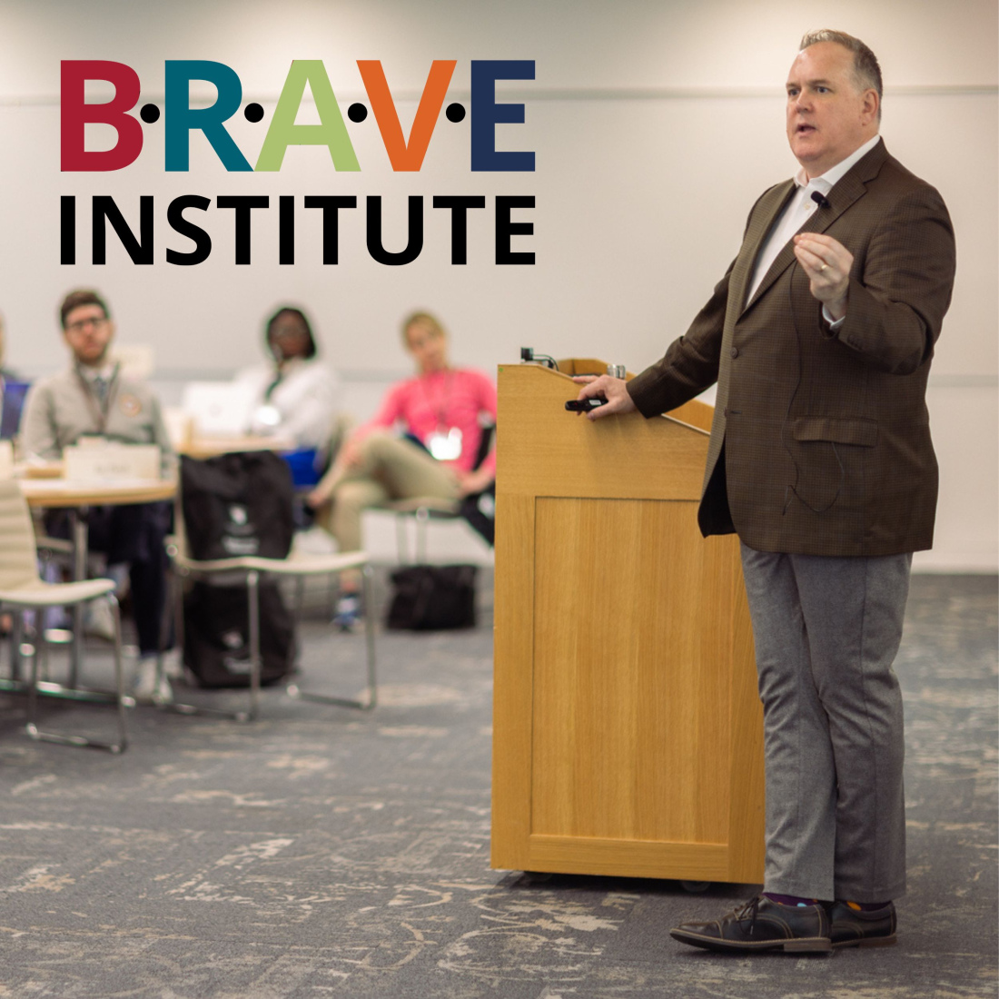 Faculty Chair Timothy McCarthy speaking during institute on campus with colorful BRAVE logo
