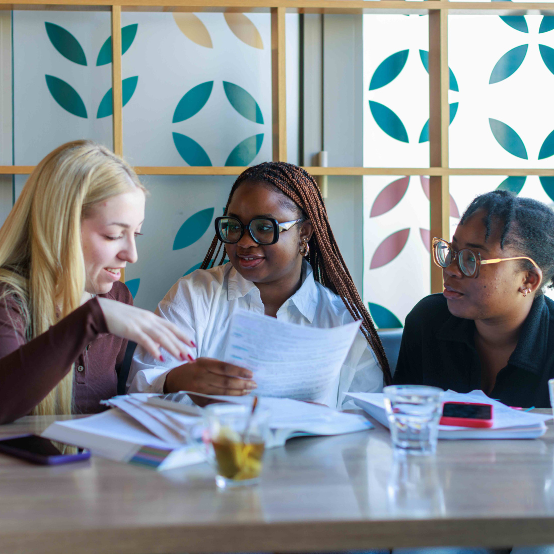 Three happy colleagues sitting in a coffee shop and collaborating