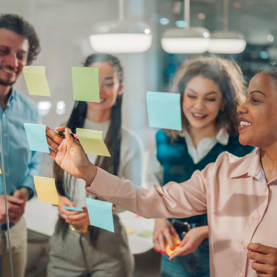 A team collaborating on a project, using sticky notes on a glass wall