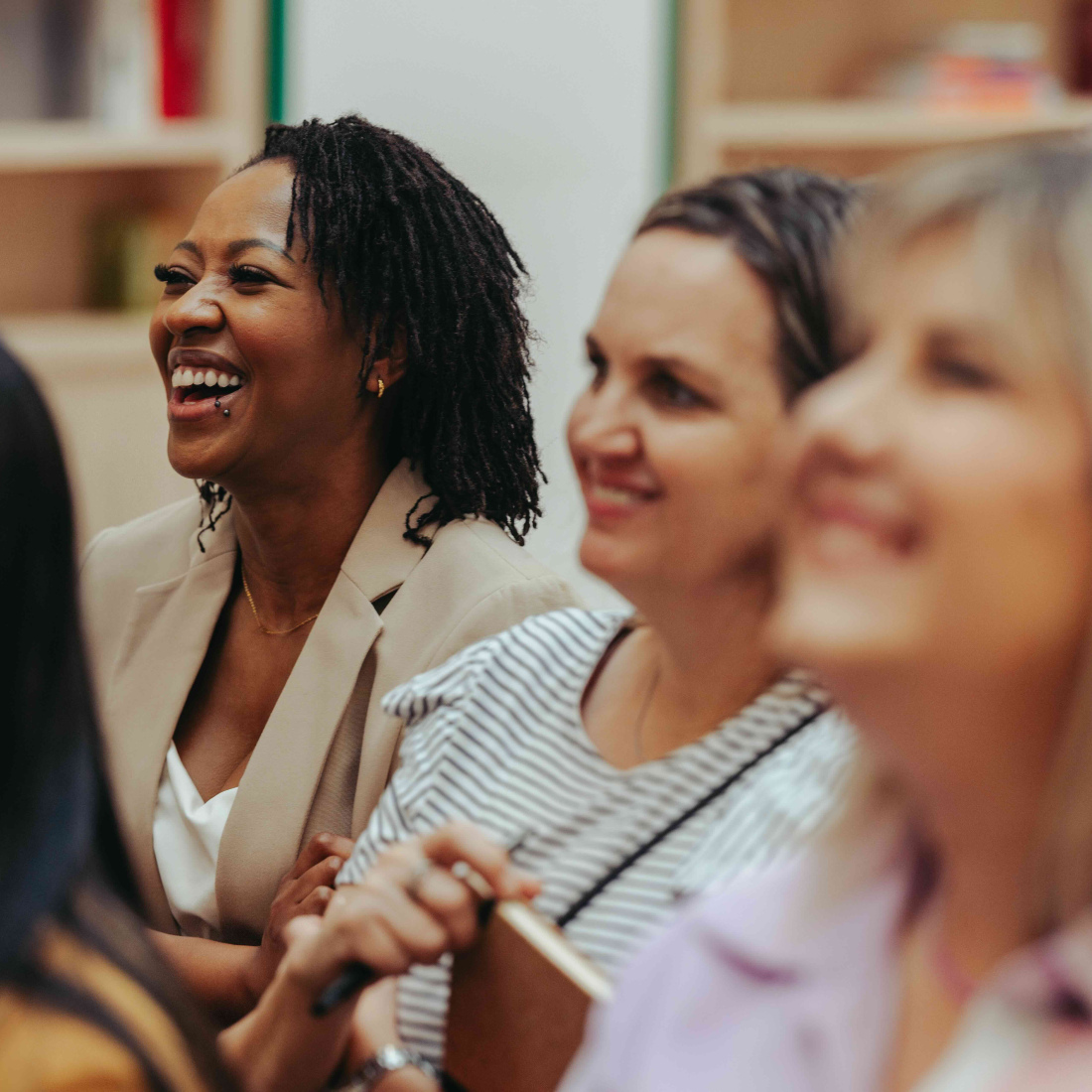 Diverse group of people smiling and engaged in a business meeting, conveying a sense of collaboration and positivity. The atmosphere is professional yet friendly, highlighting teamwork.