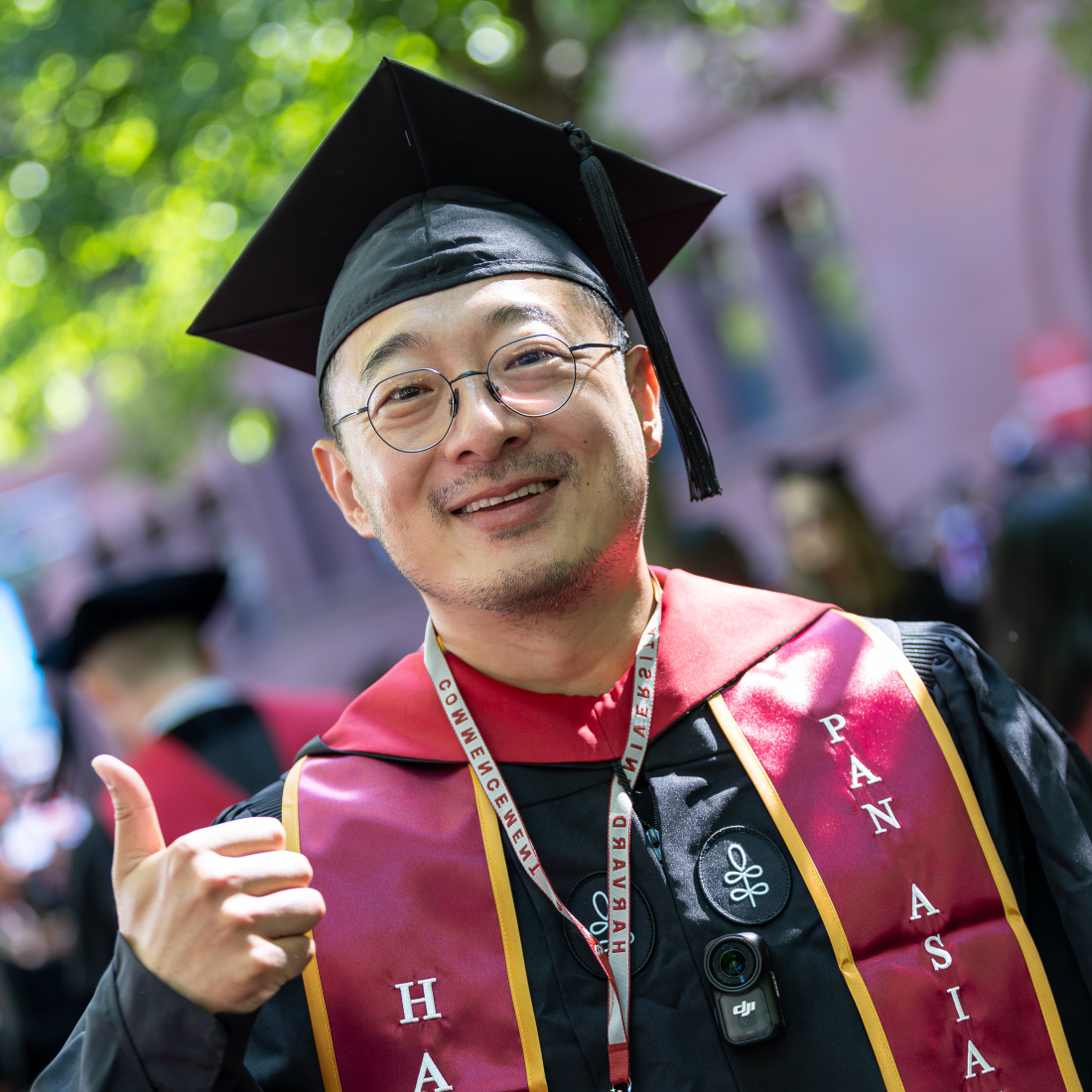 A master's student gives a thumbs up at Commencement
