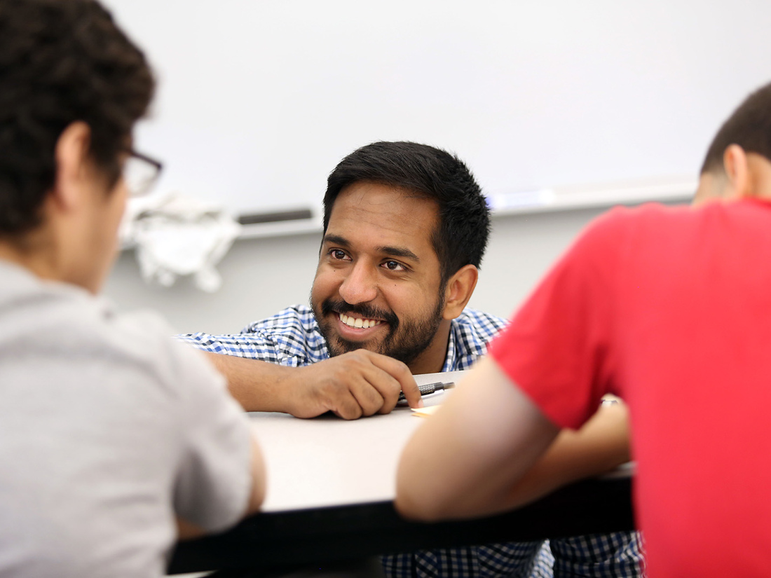A teacher smiles as he works with his students