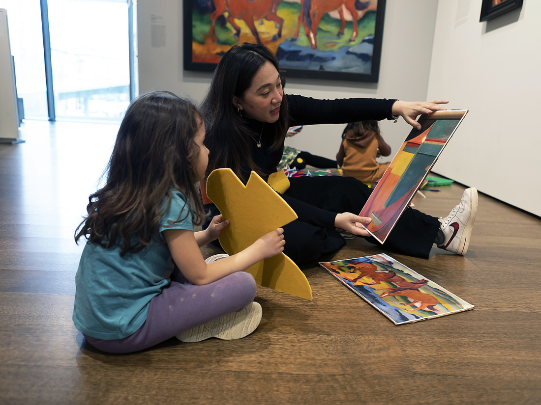 Teacher and student sitting on floor viewing art